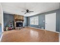 The living room has a stone fireplace, a ceiling fan, and lots of light from the windows at 401 Cabriolet Ct, Mcdonough, GA 30253