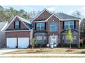 Attractive brick home with a two-car garage, well-maintained lawn, and traditional design elements at 1893 Tulip Petal Rd, Auburn, GA 30011