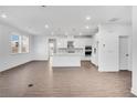 Spacious living area flows into the kitchen, showcasing wood floors, white cabinets and a center island at 6055 Misty Hill Ln, Buford, GA 30518