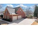 View of the house's side with a three-car garage and an expansive driveway and basketball hoop at 33 Grand Ave, Suwanee, GA 30024