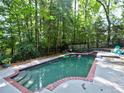 Backyard pool with safety fence and brick trim, surrounded by lush greenery at 7440 Princeton Trce, Sandy Springs, GA 30328