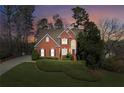 Twilight view of a red brick home, featuring a lush lawn and mature trees at 340 Ruby Forest Pkwy, Suwanee, GA 30024