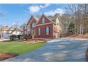 Brick two-story home with a long driveway, attached garage, and a well-maintained lawn with mature trees at 455 Emerald Lake Path, Sugar Hill, GA 30518