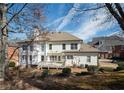Back of house view with a white exterior, deck, well-maintained yard, and mature trees at 6195 Mountainwell Dr, Roswell, GA 30075