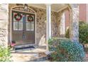 Elegant entrance with stone archway, double doors adorned with wreaths, and lush greenery at 3529 S Sherwood Se Rd, Smyrna, GA 30082