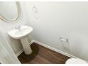 Small half bathroom with pedestal sink, chrome hardware, oval mirror and wood flooring at 8664 Webb Rd, Riverdale, GA 30274