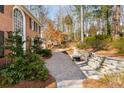 Paver walkway with a brick retaining wall leads to the home, surrounded by trees and shrubs at 355 Highlands Trce, Roswell, GA 30075