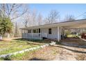 Single-story home with a covered porch, carport, and stone-lined flowerbeds framing the front yard at 3642 Highway 81, Oxford, GA 30054
