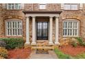 Elegant front entrance with stately columns, stone walkway, and a classic black double door design at 2310 Gracehaven Way, Lawrenceville, GA 30043