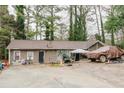 Side angle view of a single story tan home, featuring a vehicle covered in a tarp and deciduous trees around it at 5461 Chuzzlewit Sw Ct, Lilburn, GA 30047