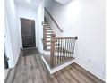 Inviting entryway showcasing wood-look flooring and a staircase with modern black iron spindles at 3255 Bartee Walk, Suwanee, GA 30024