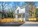 Inviting two-story home featuring a cozy front porch and a gravel driveway, surrounded by lush trees and a wooden fence at 1088 Wedgewood Nw Dr, Atlanta, GA 30318