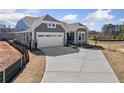 A view of the home showcasing the long driveway, two-car garage, and landscaping, on a partially sunny day at 144 Laurel Farms Ln, Dallas, GA 30157