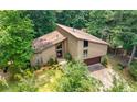 Exterior shot of a multi-story home with a two-car garage, surrounded by lush trees and greenery at 2235 Six Branches Dr, Roswell, GA 30076