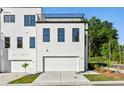 Rear view of a modern townhome with a garage and a rooftop deck on a sunny day at 2150-5 Tidwell Ln # 5, Atlanta, GA 30318