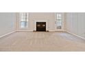 Spacious living room featuring plush carpeting, a cozy fireplace, and a door to a private outdoor space at 6420 Magnolia Way, Morrow, GA 30260