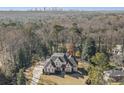 Expansive aerial view of a luxurious home nestled among lush trees with a city skyline in the distance at 1005 W Kingston Dr, Atlanta, GA 30342