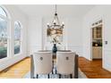 Formal dining room featuring hardwood floors, a modern chandelier, wainscoting, and abundant natural light through large windows at 5170 Deerlake Dr, Alpharetta, GA 30005