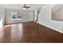 Open-concept living room with hardwood floors, gray walls, ceiling fan, and staircase at 1100 Cotton Gin Dr, Woodstock, GA 30188