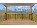 Covered back porch with a wood railing overlooking the backyard and trees at 4770 Briscoe Dr, Cumming, GA 30028