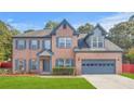 Charming two-story brick home with blue shutters, attached garage, and well-manicured lawn at 1021 Adah Ln, Lawrenceville, GA 30043