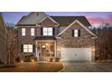 Beautiful two-story brick home with attached two car garage, front porch, and a colorful sunset at 242 Crestbrook Ln, Dallas, GA 30157