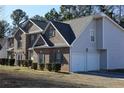 Side view of two-story brick and siding home with a two car garage and manicured bushes at 2270 Exchange Se Pl, Conyers, GA 30013