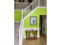 Bright foyer with lime green accent wall, white staircase and wooden floors at 2270 Exchange Se Pl, Conyers, GA 30013