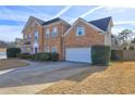 A brick home with a well-manicured lawn, an attached garage, and a paved driveway at 1225 Sand Knoll Sw Run, Lilburn, GA 30047