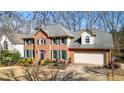 Two-story brick home featuring a two-car garage, manicured landscaping, and an American flag at 4314 Deep Springs Nw Ct, Kennesaw, GA 30144