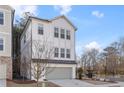 Stylish three-story home with white siding and gray garage door, set against a backdrop of trees at 120 Pinecone Pkwy, Alpharetta, GA 30022