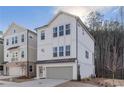 Attractive three-story home with white painted brick and siding, a gray garage door, and large windows at 120 Pinecone Pkwy, Alpharetta, GA 30022