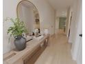 Inviting hallway featuring light wood floors, a decorative mirror, and a stylish console table with lamps and greenery at 326 Treble Way, Alpharetta, GA 30009