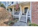 Inviting front porch with classic white railings, an American flag, and a welcoming entrance at 245 Bartlett Dr, Sharpsburg, GA 30277