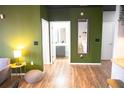 Stylish hallway with green accent wall leads to a modern bathroom with gray vanity and wood-look floors at 898 Oak Sw St # 1410, Atlanta, GA 30310