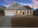 Inviting two-story home featuring a brick facade, attached garage, and manicured lawn under a twilight sky at 7995 Brewton Creek Dr, Cumming, GA 30028