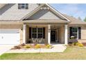 Charming brick home with a welcoming front porch, complemented by a table and chairs, and beautiful landscaping at 7995 Brewton Creek Dr, Cumming, GA 30028