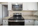 Modern kitchen features stainless steel microwave and range, granite countertops, and white cabinetry at 1433 Dennis Dr, Decatur, GA 30032