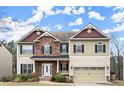 Charming two-story home featuring a stone facade, attached two-car garage, and a covered front porch at 3680 Falling Leaf Ln, Cumming, GA 30041