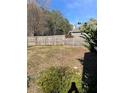 View of a backyard with a wooden fence, trees, and a small bush in the foreground at 232 Rockingham Dr, Loganville, GA 30052