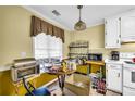 Cozy eat-in kitchen with window, featuring white appliances, bright yellow walls, and hanging light fixture at 3434 Saddlebrook Dr, Loganville, GA 30052
