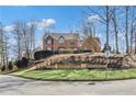 Charming two-story brick home with lush landscaping, set against a beautiful blue sky at 5435 Heathridge Ter, Johns Creek, GA 30097