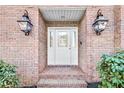 Welcoming front entrance with brick facade, brick walkway, stylish lanterns, and lush plants at 5435 Heathridge Ter, Johns Creek, GA 30097