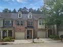 Daytime view of a brick townhome with a two-car garage and classic architectural details at 1649 Southgate Mill Dr, Duluth, GA 30096