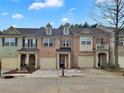 Well-maintained townhome showcasing a brick facade, individual garages, and landscaped front yards at 1649 Southgate Mill Dr, Duluth, GA 30096