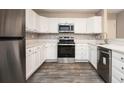 Well-lit kitchen featuring stainless steel appliances, stylish backsplash, and white cabinets and countertops at 5474 Post Road Pass, Stone Mountain, GA 30088