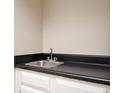 Wet bar featuring a stainless steel sink, black countertops and white cabinets at 5474 Post Road Pass, Stone Mountain, GA 30088