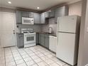 Bright kitchen featuring white appliances, gray cabinets, subway tile backsplash, and tile flooring at 197 Upshaw Sw St, Atlanta, GA 30315