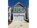 New construction two-story townhome showcases a 2-car garage, gray siding, and freshly painted white brick at 1587 Aiden Way # 43, Conyers, GA 30013