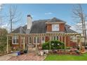 Expansive back exterior featuring a pergola, brick-paved patio, and manicured landscaping at 3620 Highpoint Rd, Cumming, GA 30041